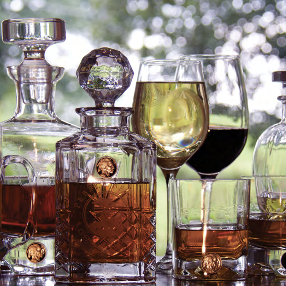 Two decanters with liquid and two wine glasses filled with different types of wine on a wooden surface.